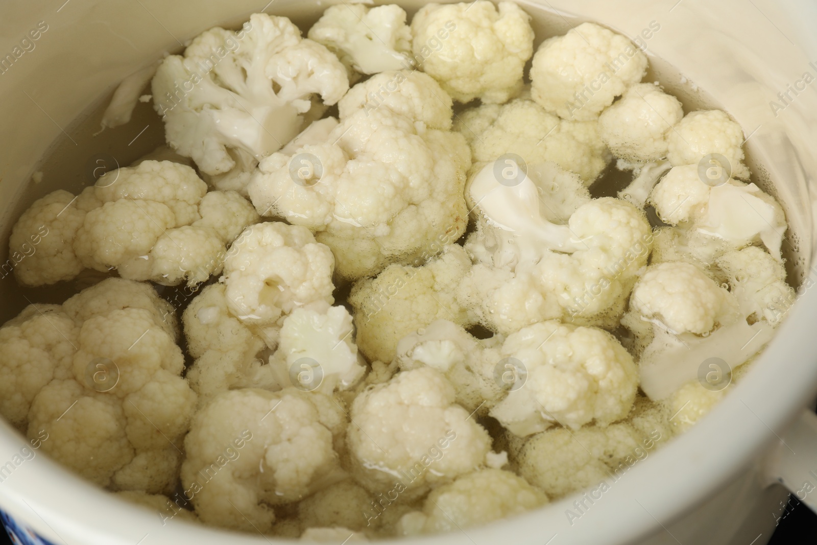 Photo of Cooking cauliflower. Florets in white pot with water, closeup