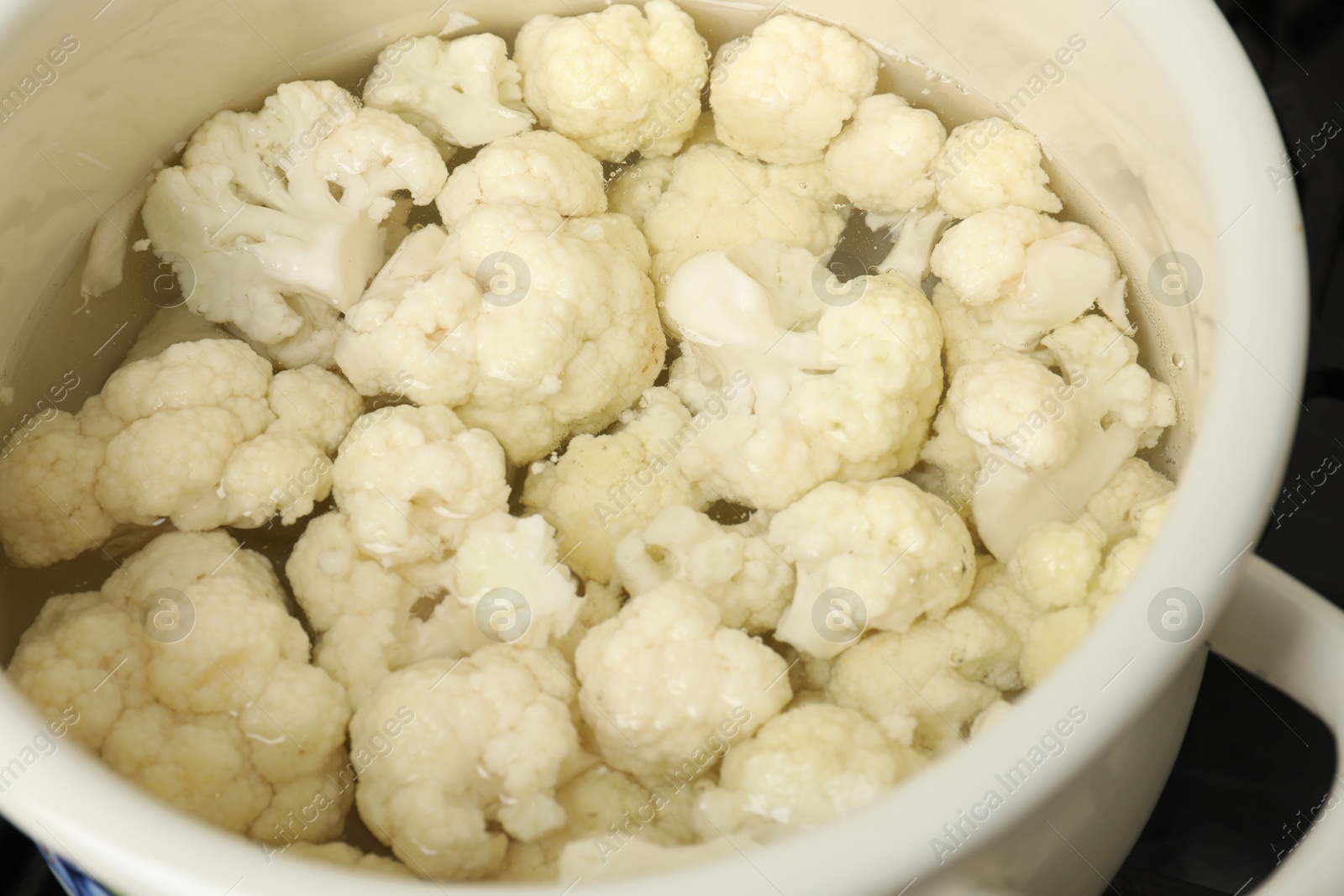 Photo of Cooking cauliflower. Florets in white pot with water, closeup