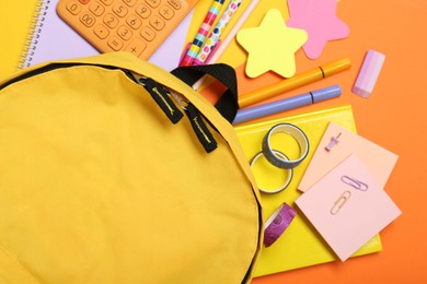 Backpack and different school stationery on color background, flat lay