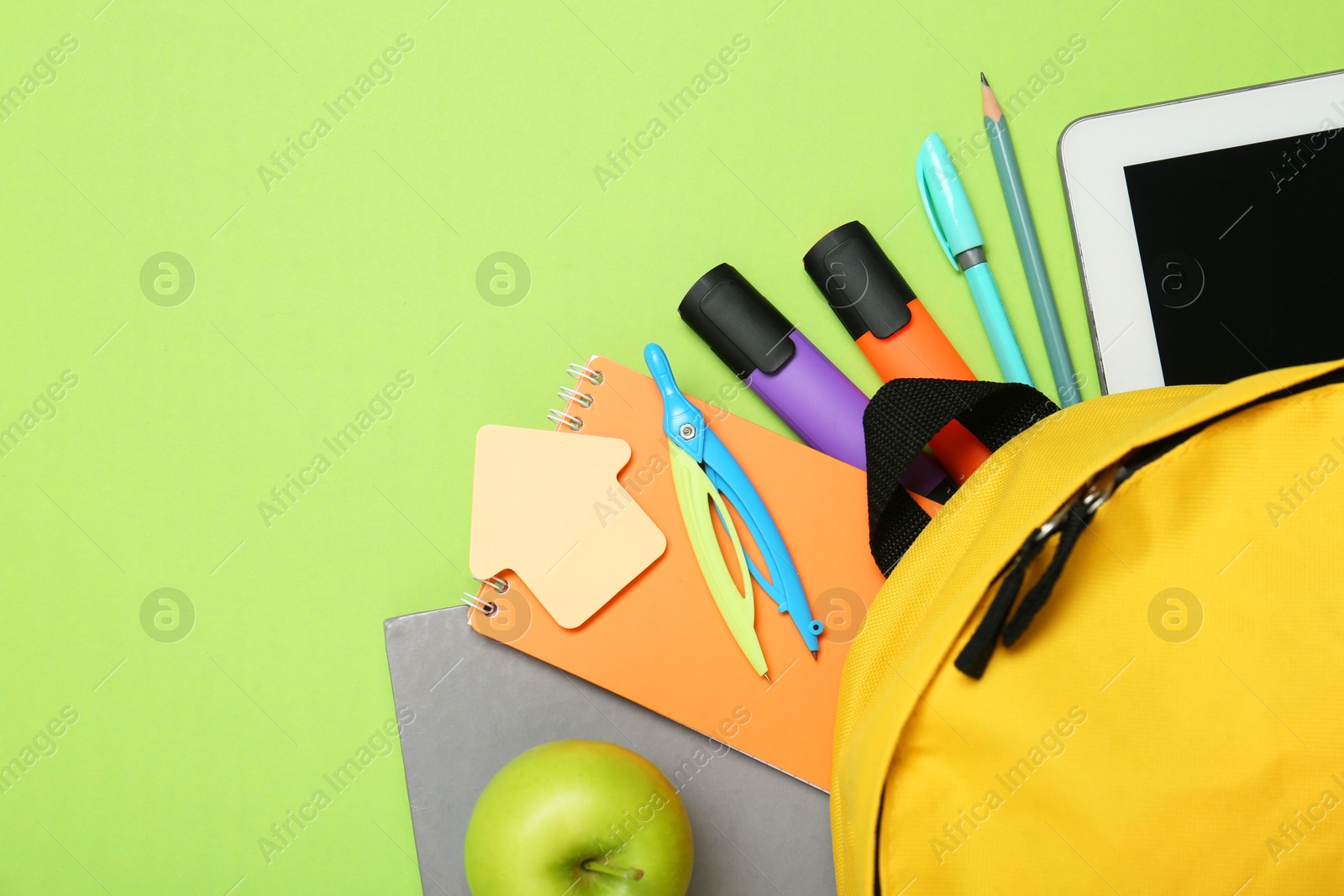 Photo of Backpack, different school stationery and apple on light green background, flat lay. Space for text