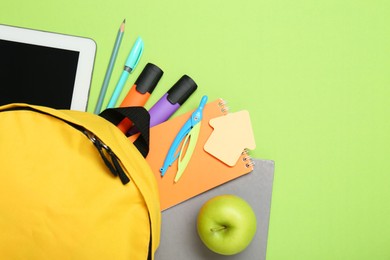 Photo of Backpack, different school stationery and apple on light green background, flat lay. Space for text