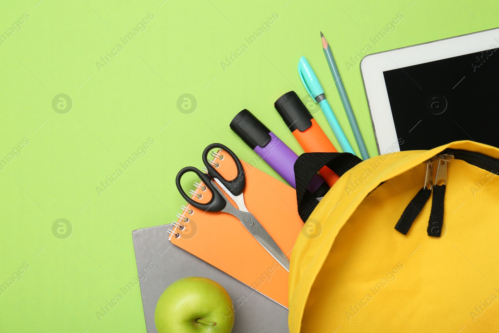 Photo of Backpack, different school stationery and apple on light green background, flat lay. Space for text