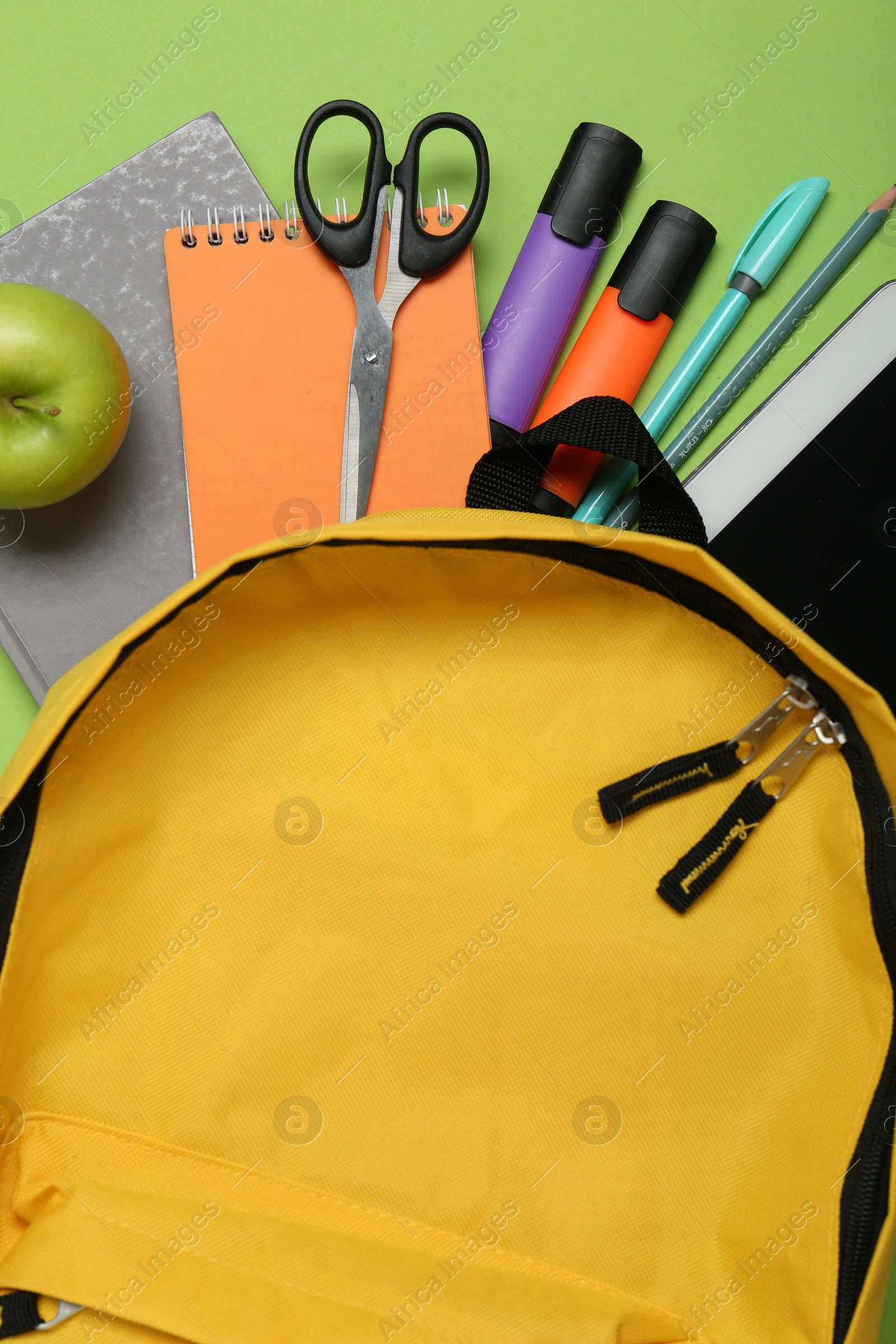 Photo of Backpack, different school stationery and apple on light green background, flat lay