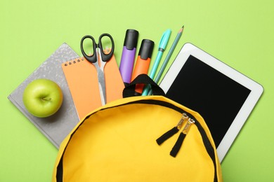 Photo of Backpack, different school stationery and apple on light green background, flat lay