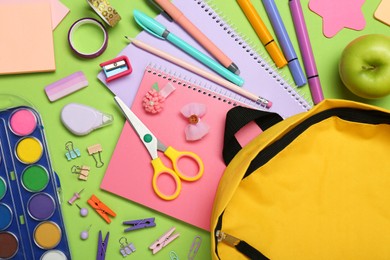 Photo of Backpack, different school stationery and apple on light green background, flat lay