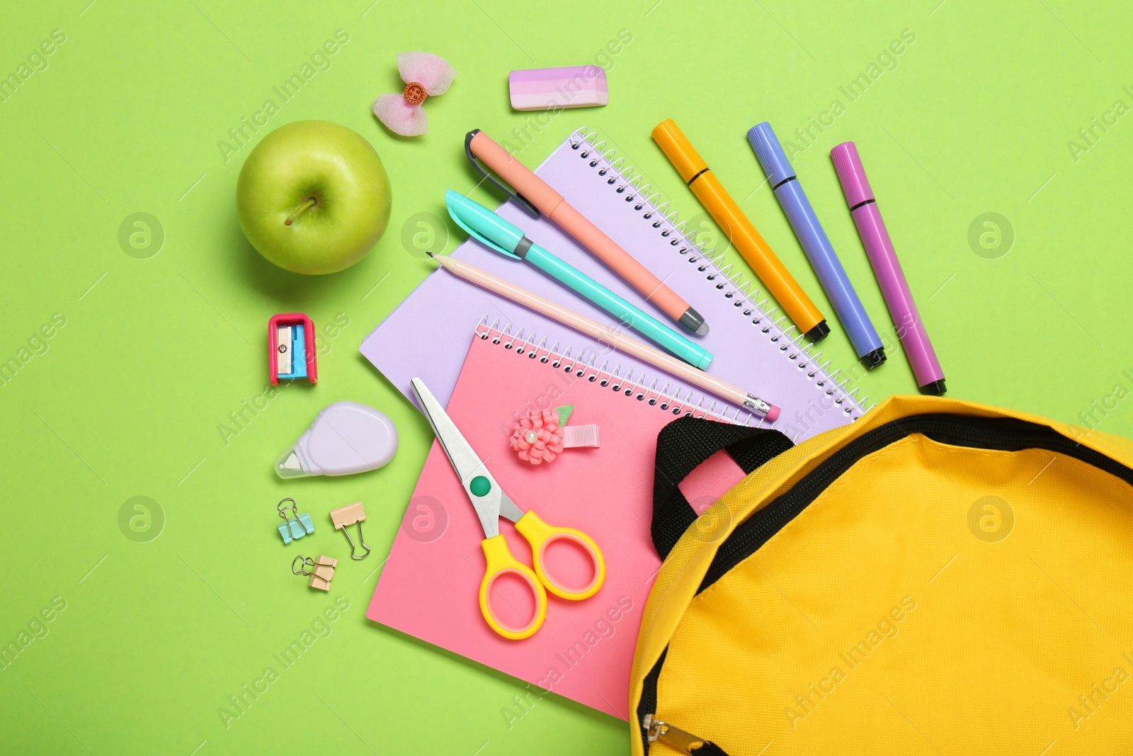 Photo of Backpack, different school stationery and apple on light green background, flat lay