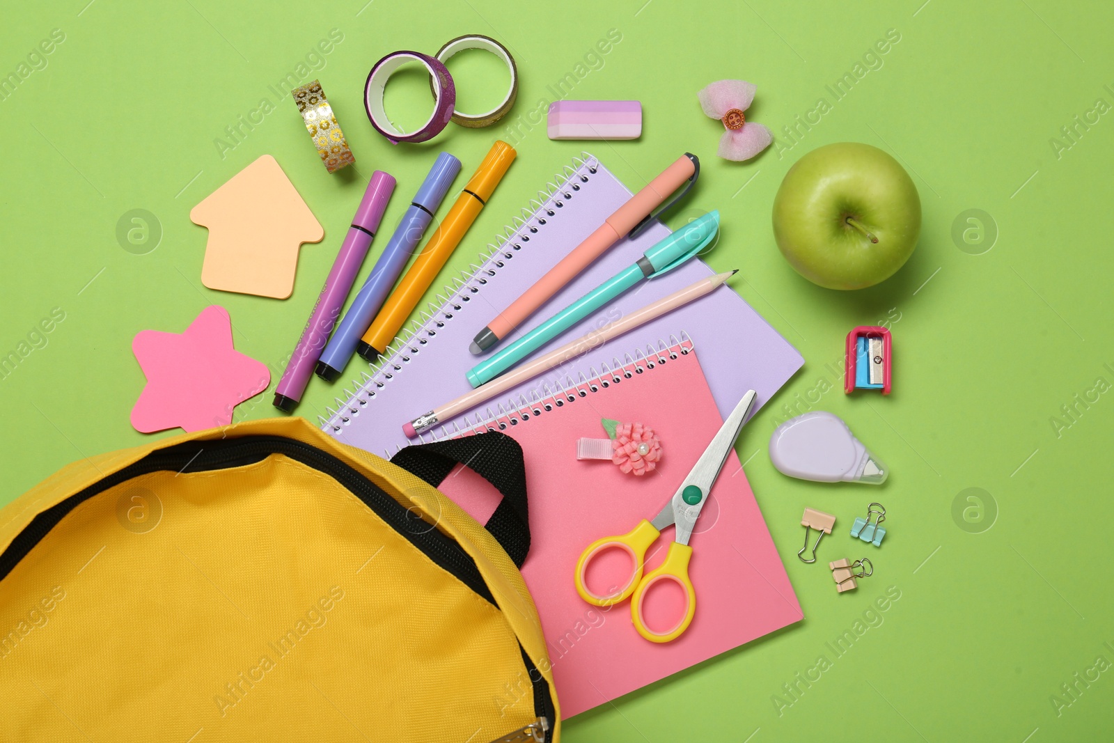 Photo of Backpack, different school stationery and apple on light green background, flat lay