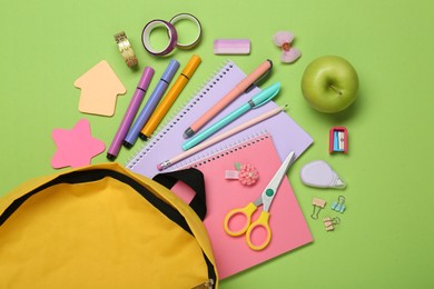 Photo of Backpack, different school stationery and apple on light green background, flat lay