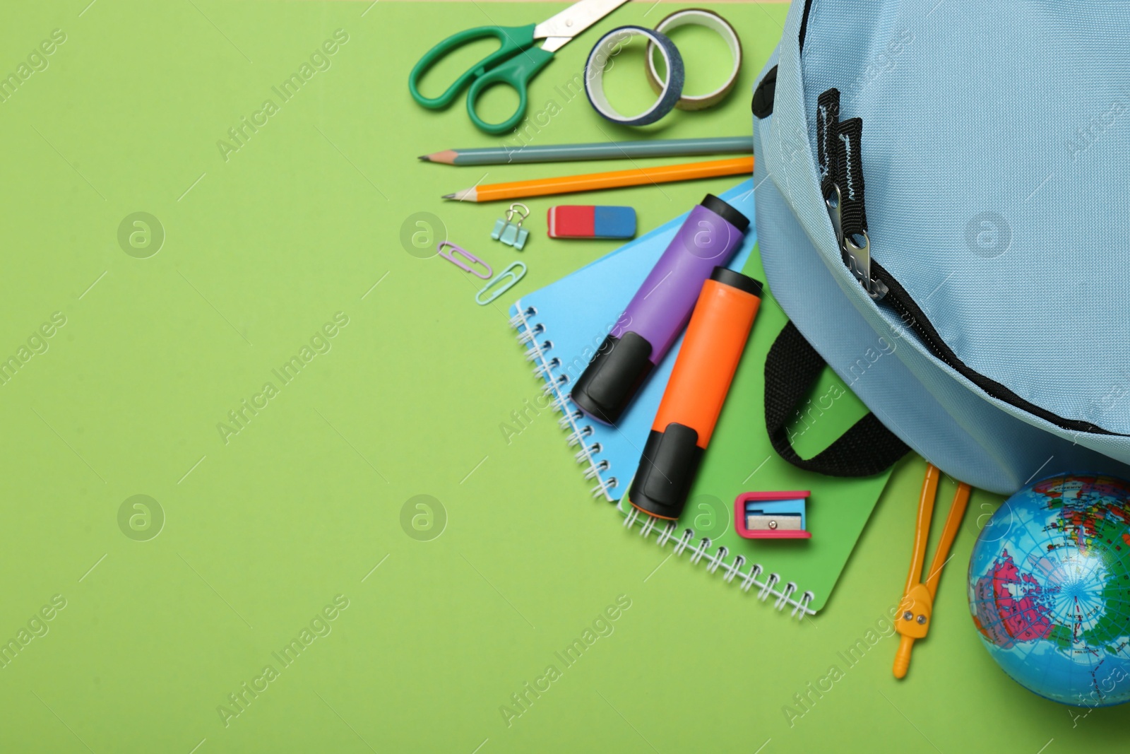 Photo of Backpack and different school stationery on light green background, flat lay. Space for text