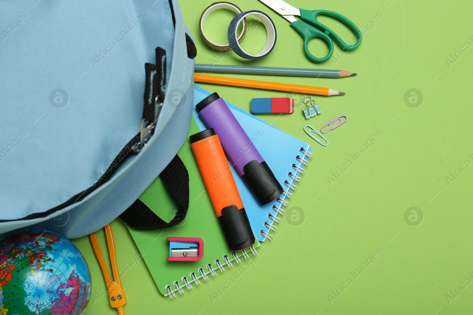 Photo of Backpack and different school stationery on light green background, flat lay. Space for text