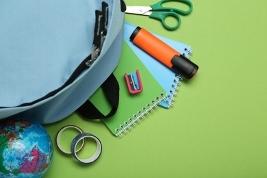 Photo of Backpack and different school stationery on light green background, flat lay. Space for text