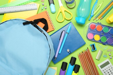 Photo of Backpack and different school stationery on light green background, flat lay