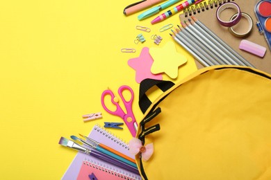 Photo of School backpack and stationery on yellow background, flat lay. Space for text