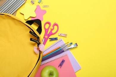 Photo of School backpack and stationery on yellow background, flat lay. Space for text