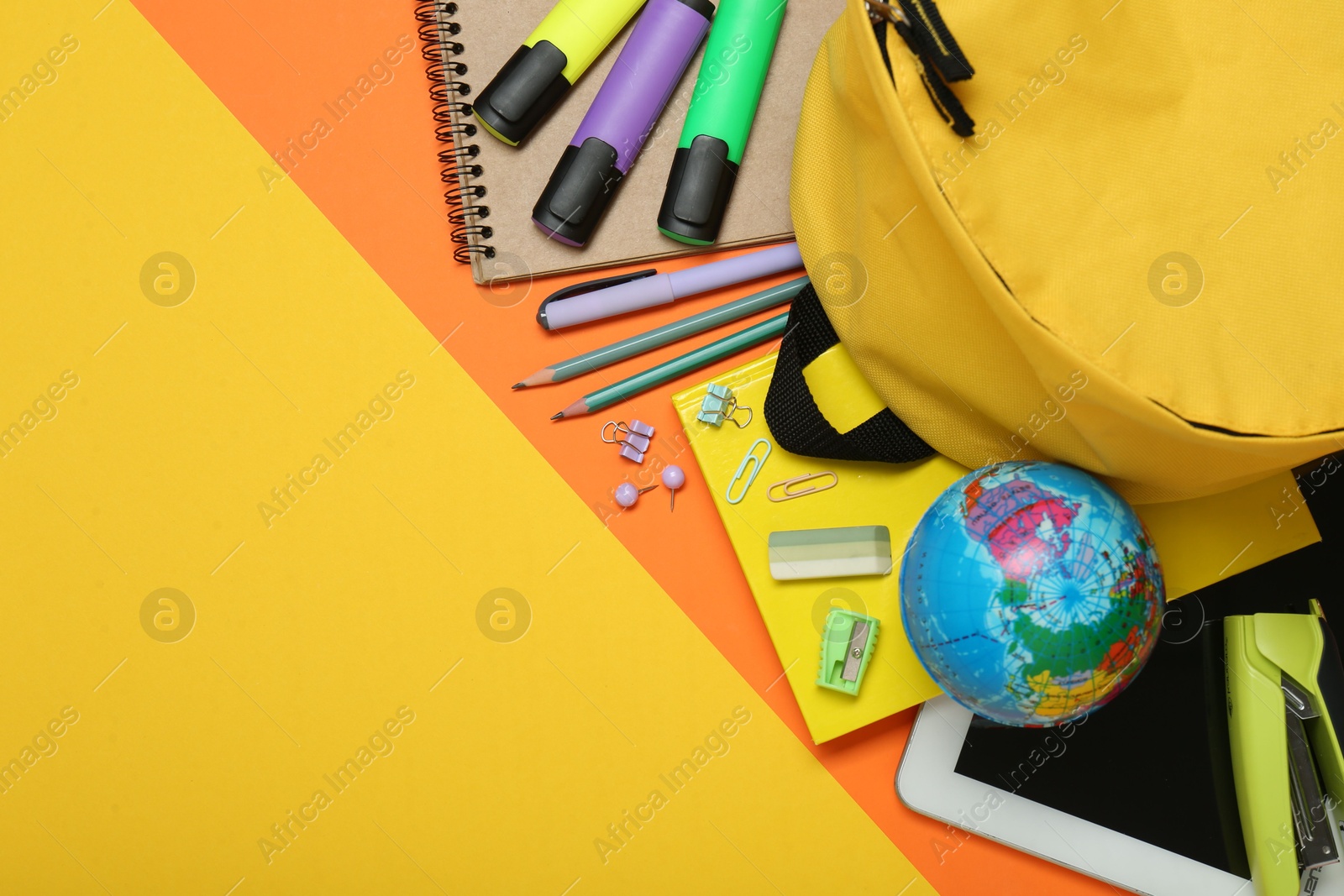 Photo of School backpack, tablet and stationery on color background, flat lay. Space for text