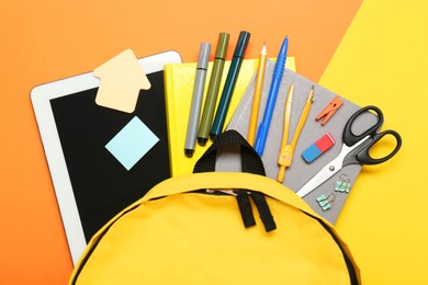 School backpack, tablet and stationery on color background, flat lay