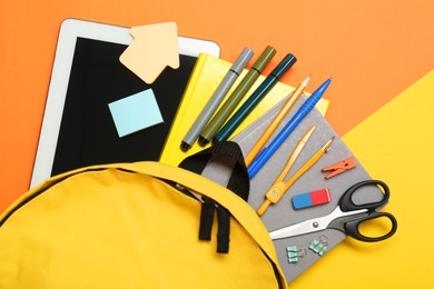 School backpack, tablet and stationery on color background, flat lay