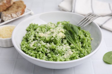 Photo of Delicious spinach risotto with parmesan cheese served on white tiled table, closeup