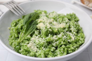 Photo of Delicious spinach risotto with parmesan cheese served on white tiled table, closeup