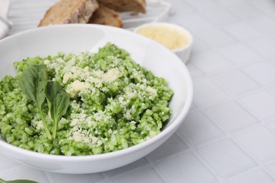 Photo of Delicious spinach risotto with parmesan cheese served on white tiled table, closeup. Space for text