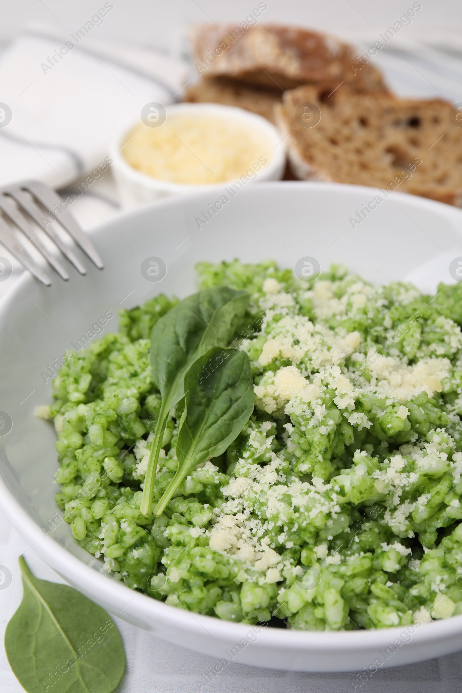 Photo of Delicious spinach risotto with parmesan cheese served on white tiled table, closeup