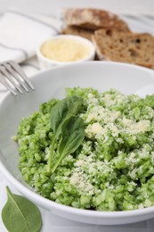 Photo of Delicious spinach risotto with parmesan cheese served on white tiled table, closeup