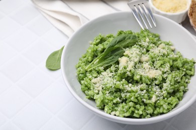 Photo of Delicious spinach risotto with parmesan cheese served on white tiled table, closeup. Space for text