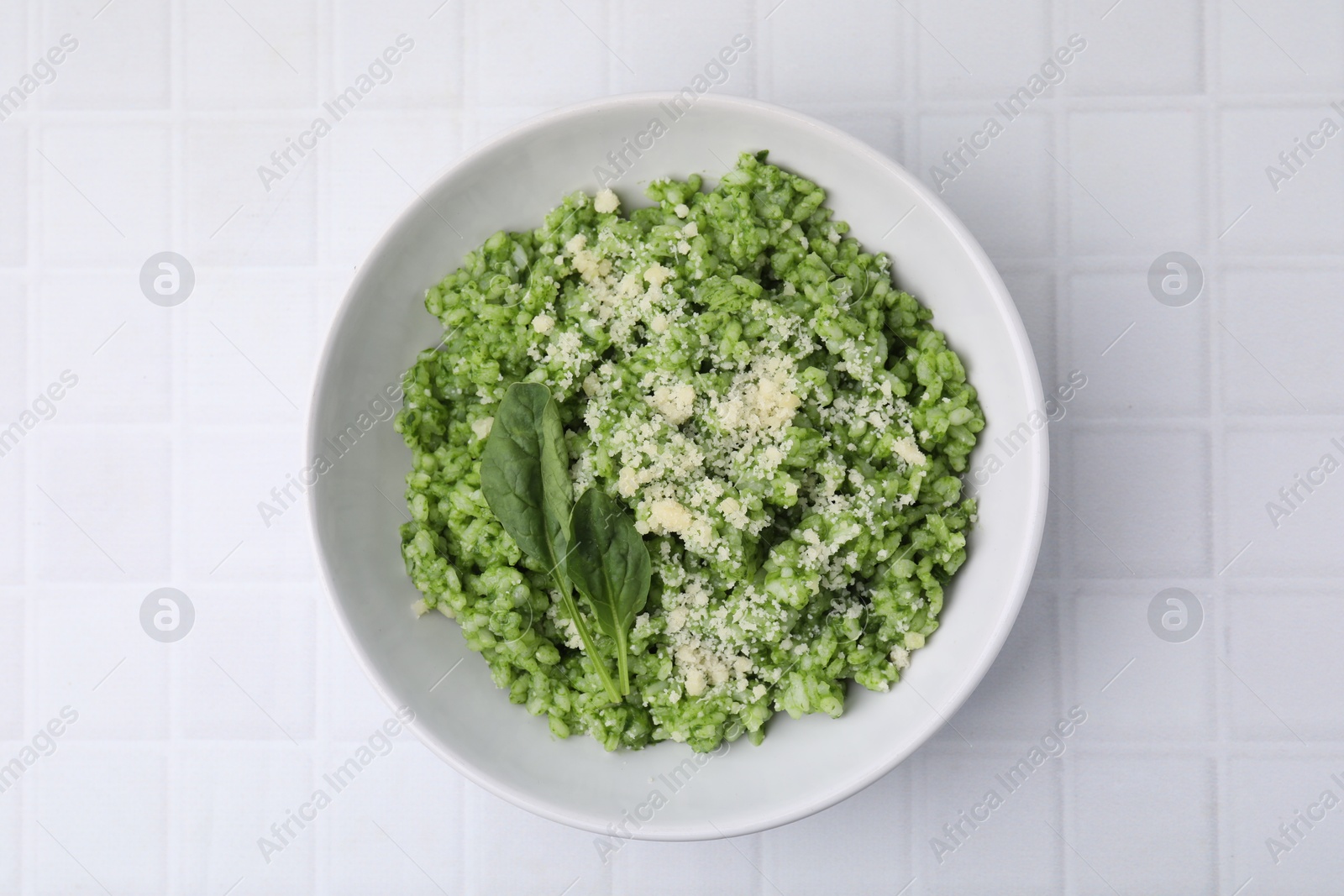 Photo of Delicious spinach risotto with parmesan cheese on white tiled table