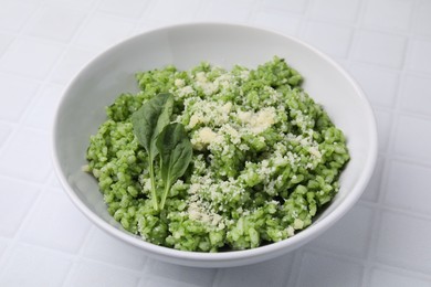 Photo of Delicious spinach risotto with parmesan cheese on white tiled table