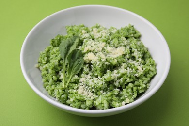 Photo of Delicious spinach risotto with parmesan cheese on light green background, closeup