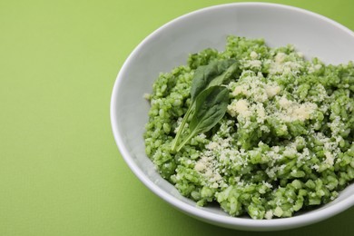 Photo of Delicious spinach risotto with parmesan cheese on light green background, closeup. Space for text