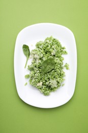 Photo of Delicious spinach risotto with parmesan cheese on light green background, top view