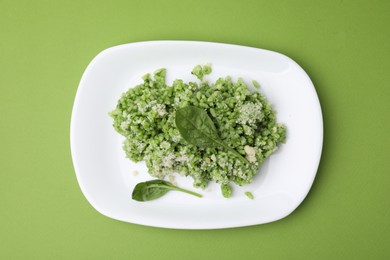 Photo of Delicious spinach risotto with parmesan cheese on light green background, top view