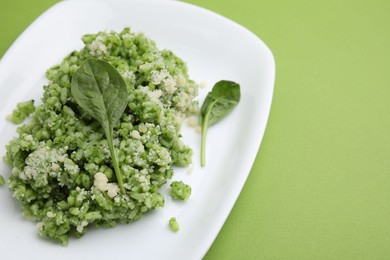 Photo of Delicious spinach risotto with parmesan cheese on light green background, closeup