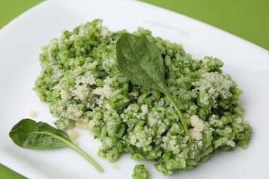 Photo of Delicious spinach risotto with parmesan cheese on light green background, closeup