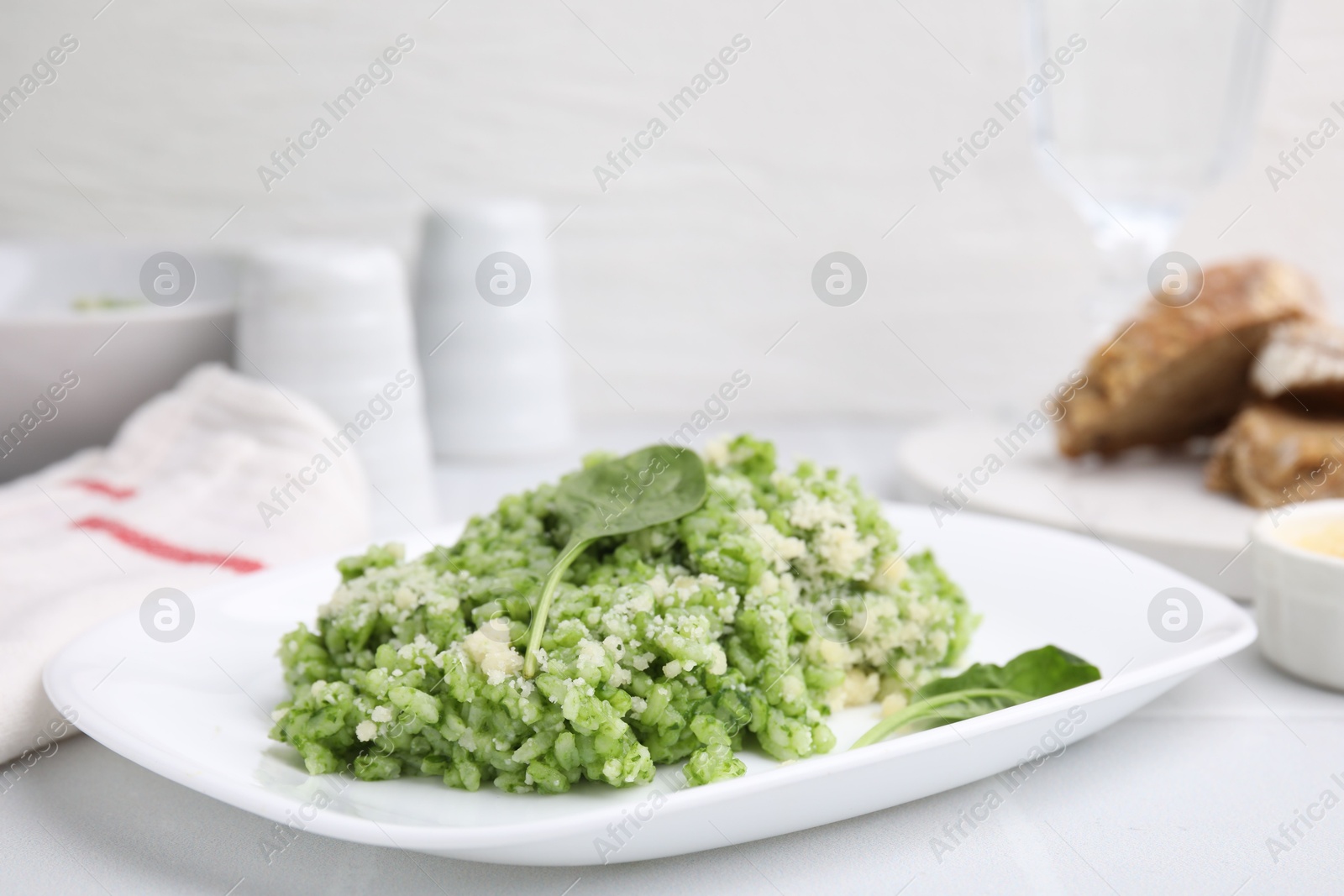 Photo of Delicious spinach risotto with parmesan cheese on white tiled table