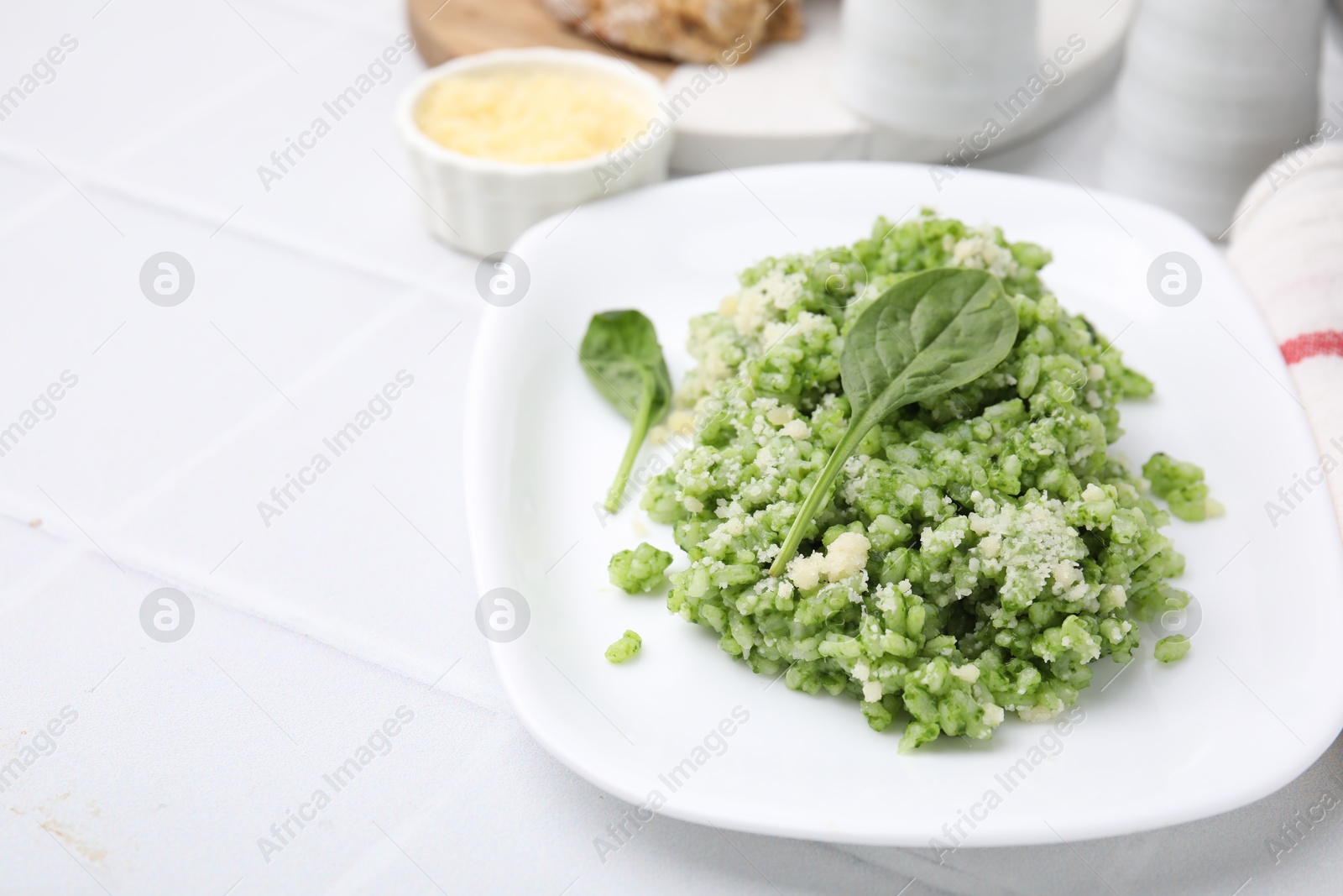 Photo of Delicious spinach risotto with parmesan cheese on white tiled table