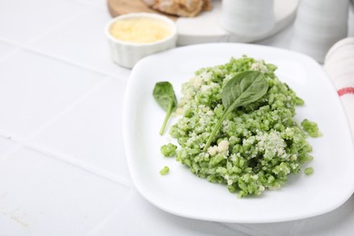 Photo of Delicious spinach risotto with parmesan cheese on white tiled table