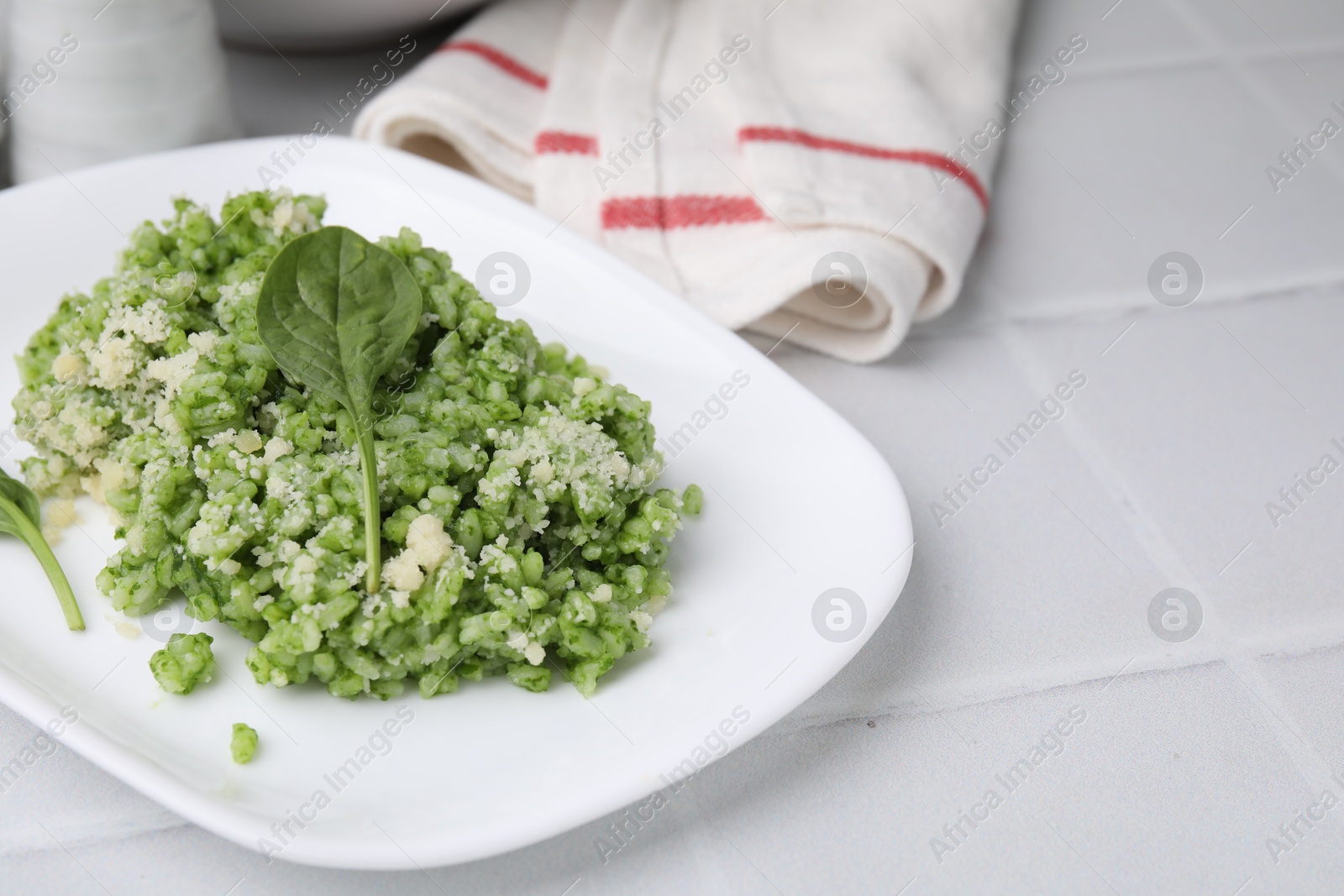 Photo of Delicious spinach risotto with parmesan cheese on white tiled table, closeup