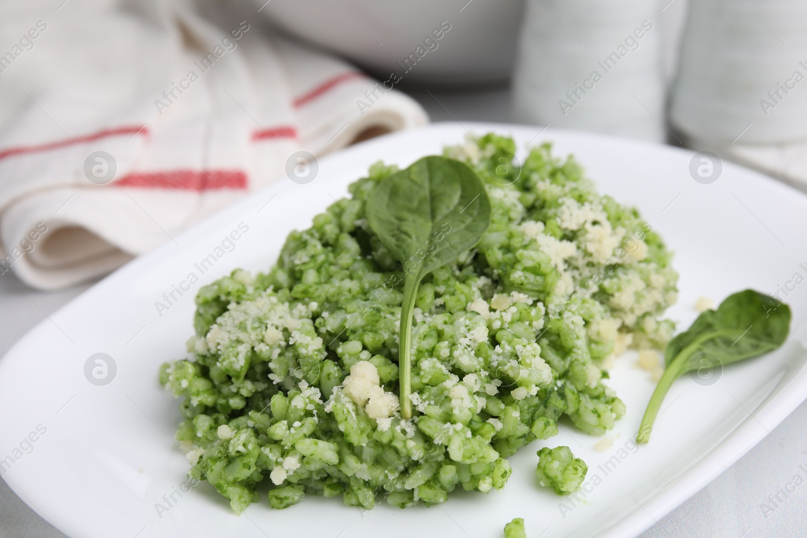 Photo of Delicious spinach risotto with parmesan cheese on white tiled table, closeup