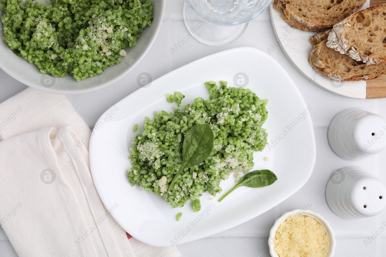 Photo of Delicious spinach risotto with parmesan cheese on white tiled table, flat lay