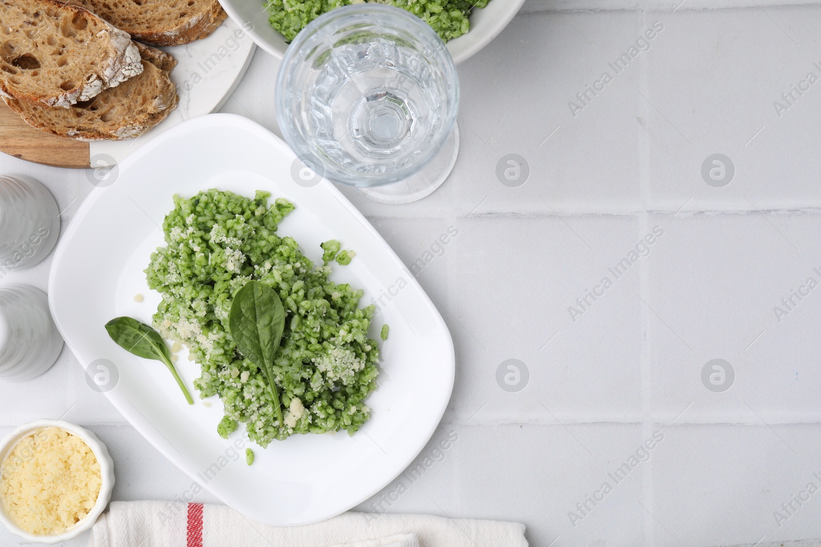 Photo of Delicious spinach risotto with parmesan cheese on white tiled table, flat lay. Space for text