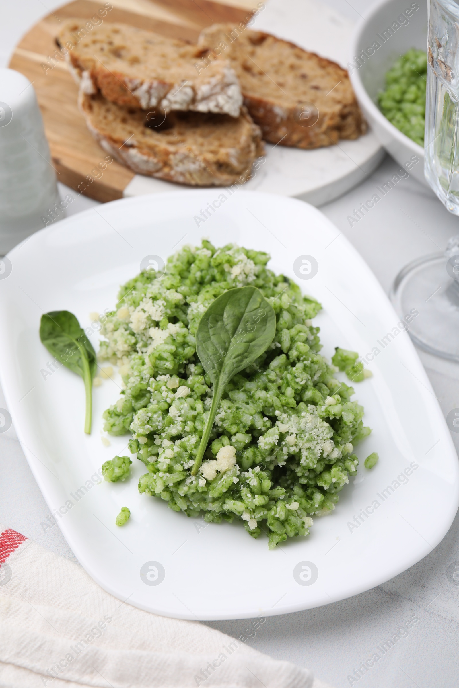 Photo of Delicious spinach risotto with parmesan cheese on white tiled table