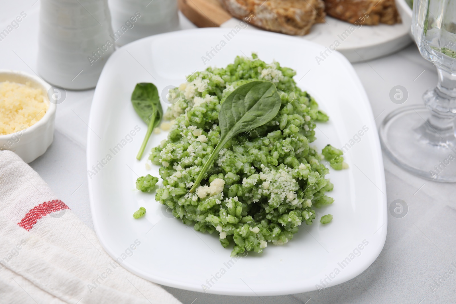 Photo of Delicious spinach risotto with parmesan cheese on white tiled table, closeup