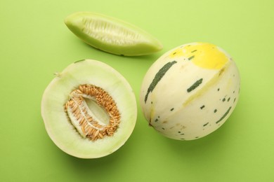 Photo of Fresh ripe honeydew melons on green background, top view