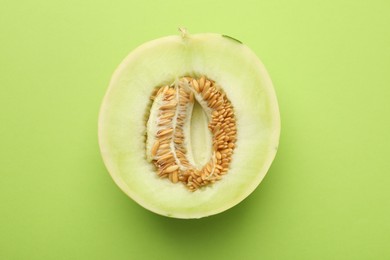 Photo of Half of fresh ripe honeydew melon on green background, top view