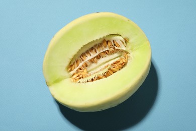 Photo of Cut fresh ripe honeydew melon on light blue background, top view