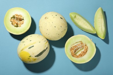 Photo of Fresh ripe honeydew melons on light blue background, flat lay