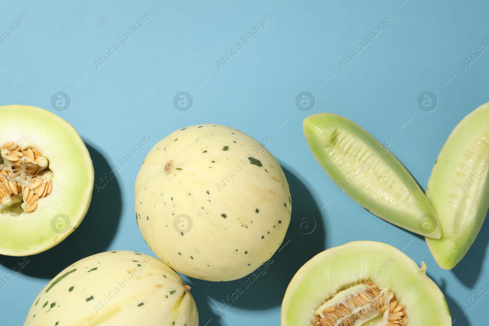 Photo of Fresh ripe honeydew melons on light blue background, flat lay