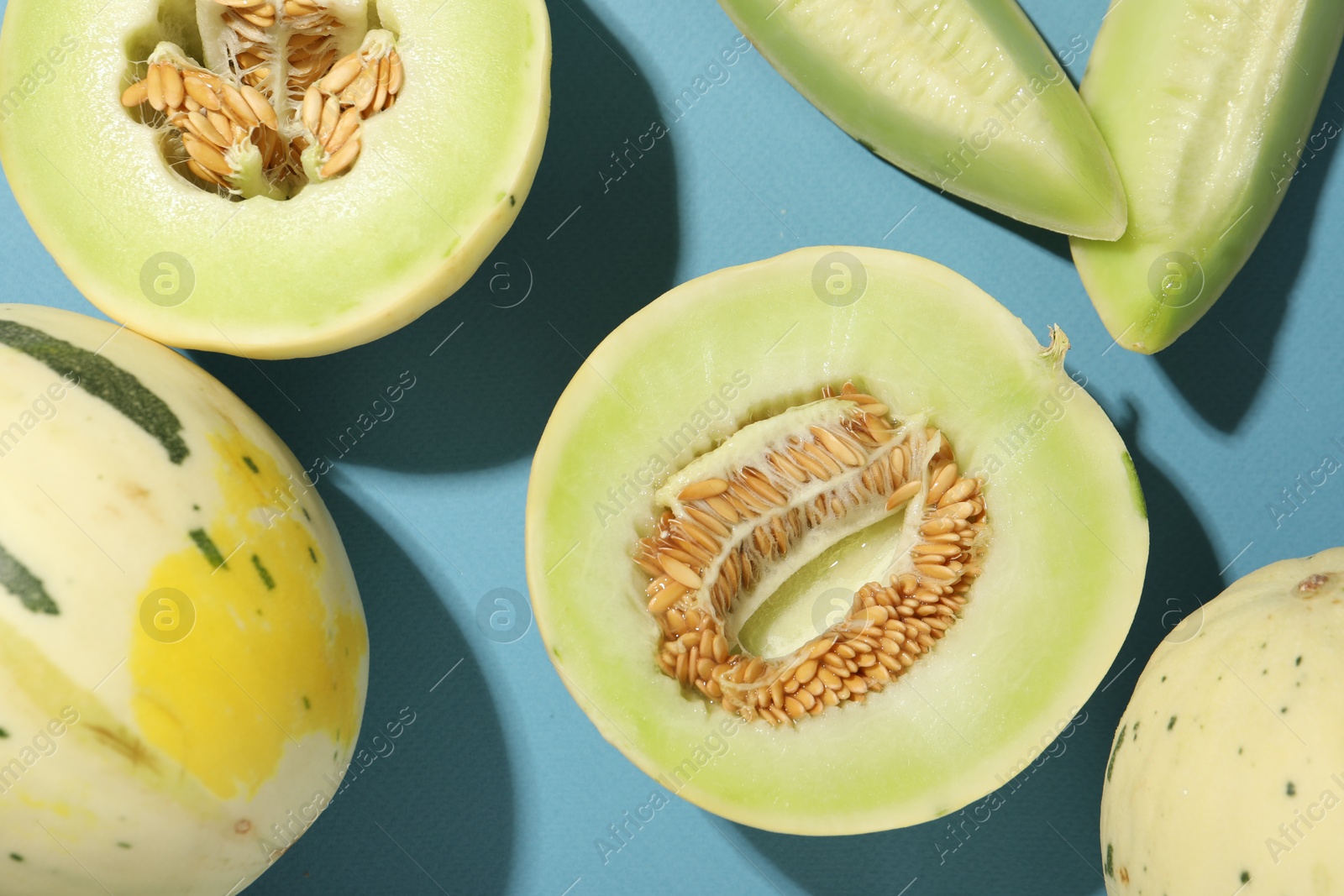 Photo of Fresh ripe honeydew melons on light blue background, flat lay